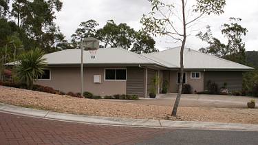 House on inclined block with basketball hoop in front yard.